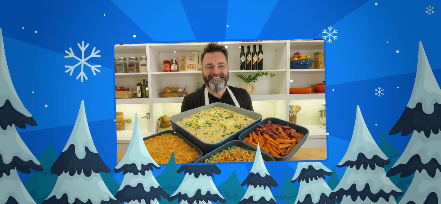 chef eric james holds all his holiday dishes on a blue background with snowy pine trees