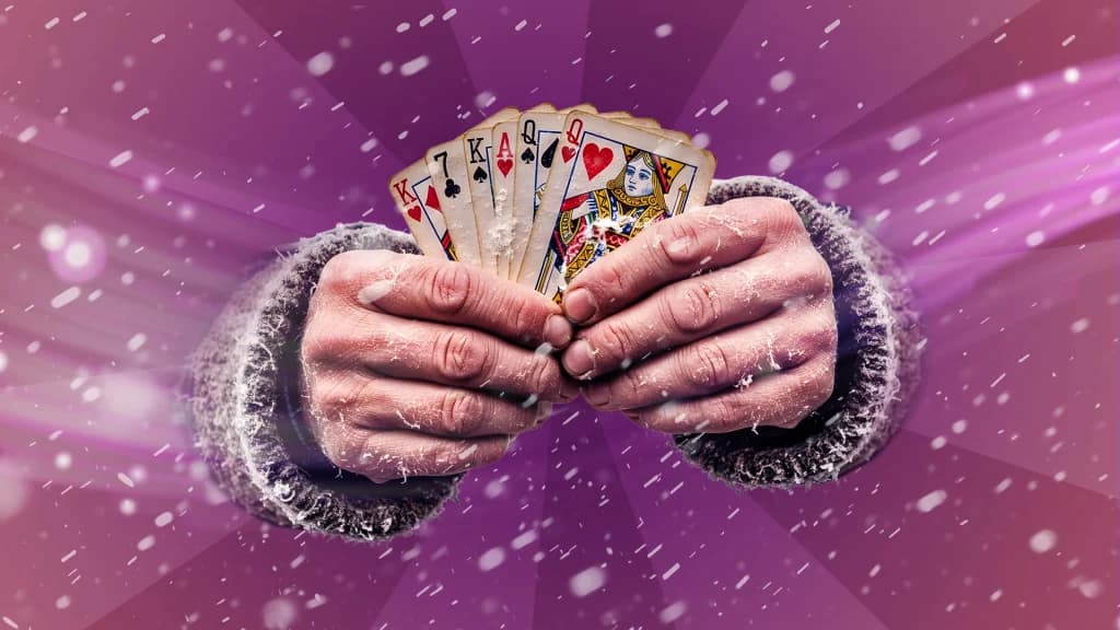 Snow drifts over a purple image, with two sweatered hands holding six cards. 