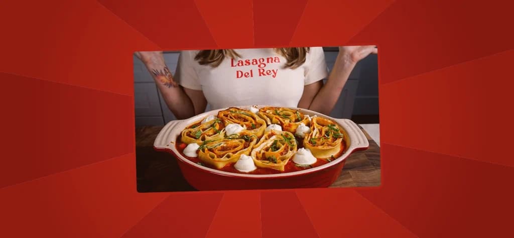 Baked pinwheel lasagna rolls arranged in a red baking dish, topped with dollops of ricotta and herbs.