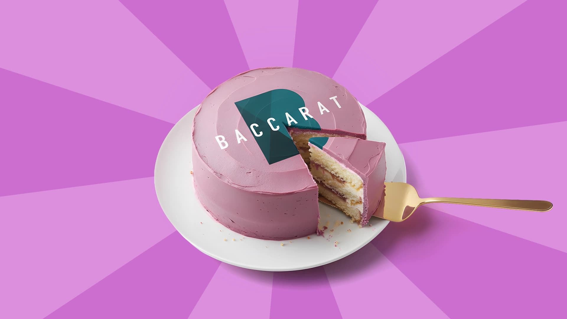 A slice of a pink cake that says, “Baccarat” is being removed on a white plate, with a purple background.