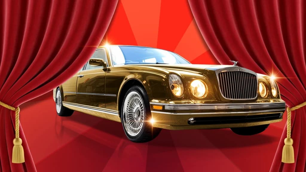 Emerging from parted red curtains is an old-school, shiny gold Bentley.