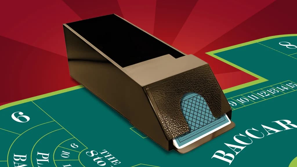 A baccarat card shoe releases a card on the green game felt.