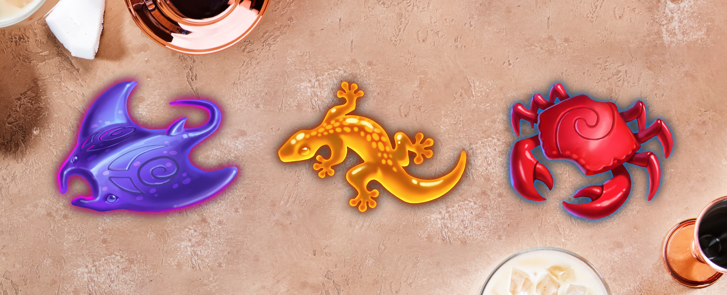 On top of a copper table surface sits a bowl, with a milk and ice drink peeking out from the bottom of the image. Featured prominently across the middle are three slot symbols from the Cafe Casino slot game, Tiki Tower, including a red crab, a yellow lizard, and a purple stingray.