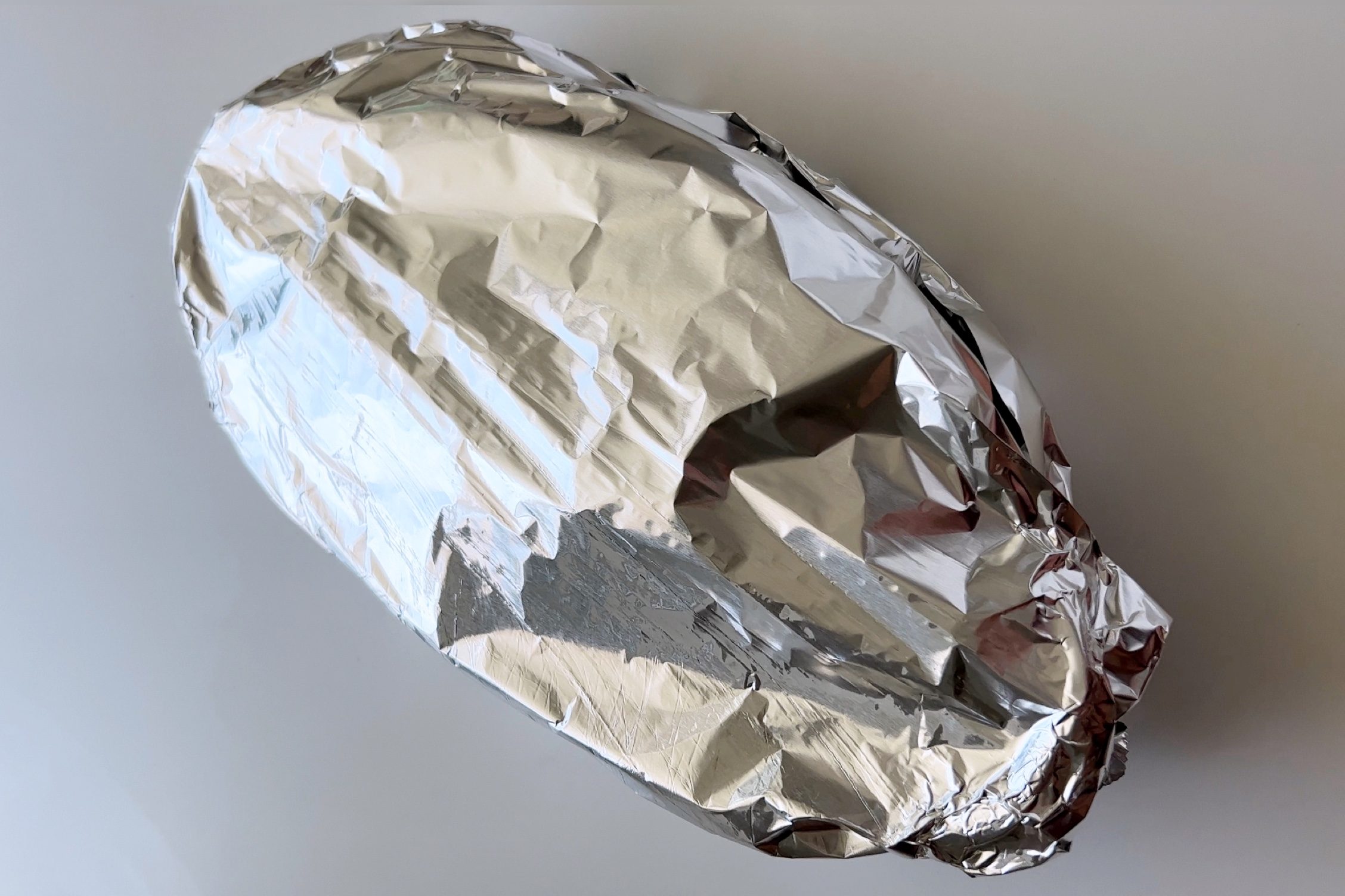 A tin foiled covered baking dish sits on a white counter.