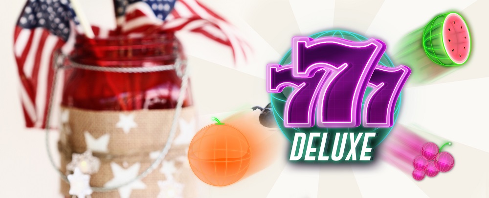 In the forefront of this game is the 777 Deluxe logo from the Cafe Casino slots game of the same name, featured in purple neon numbers, in front of a green neon globe with the word ‘deluxe’ in bold lettering below. To its left is an orange symbol, and to the right, are two fruit symbols: a watermelon and berries. In the middle distance and out of focus is a jar with USA flag toothpicks, while behind is a two-toned off-white striped background.