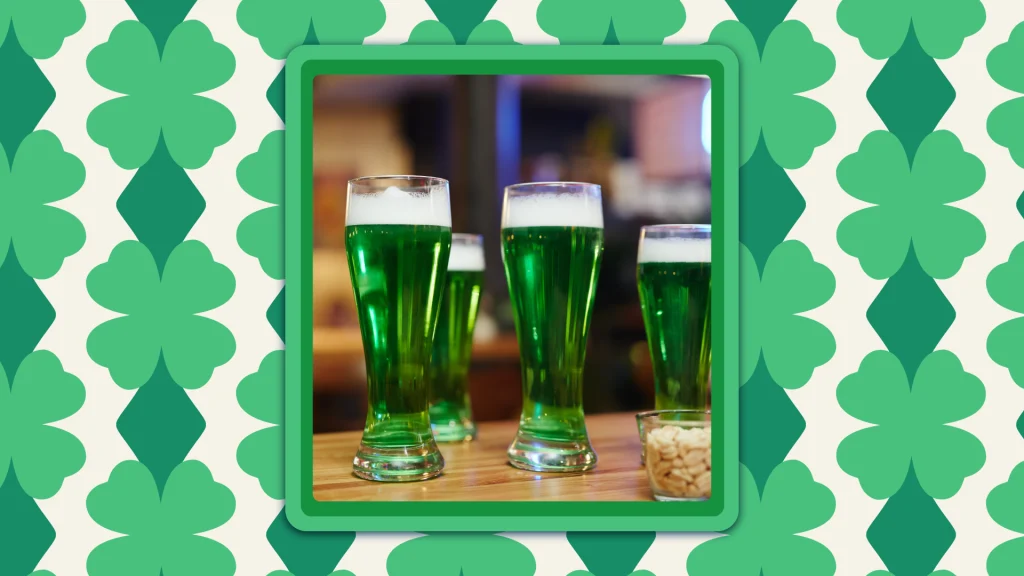 Four tall green beers stand on a wooden bar.
