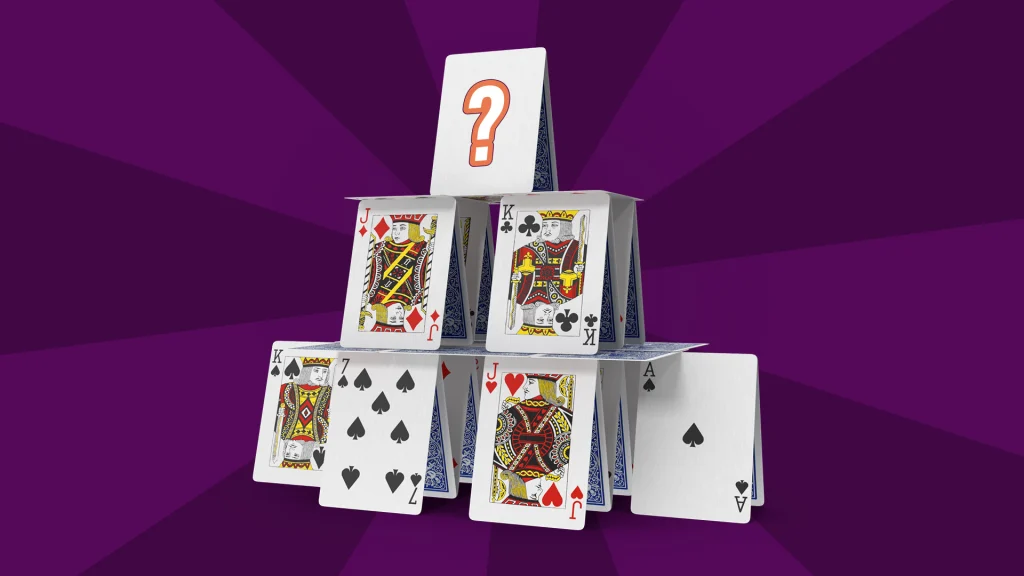 Playing cards are stacked in a pyramid on a dark blue background. On the very top is a blank white card with an orange question mark on the front. 