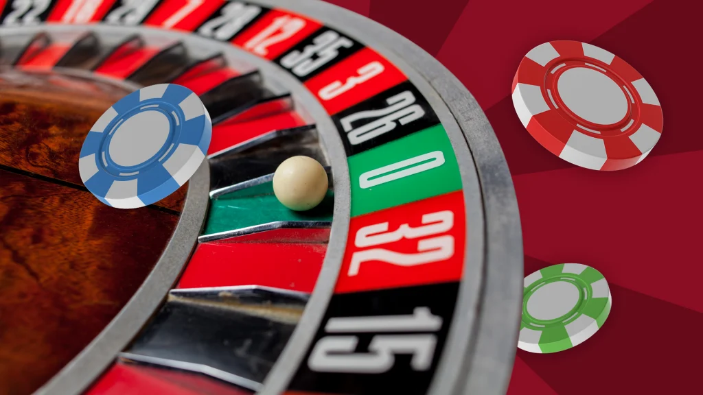 We see a roulette wheel in action with a white ball in the “0” pocket and a blue, red, and green betting chip scattered throughout. 