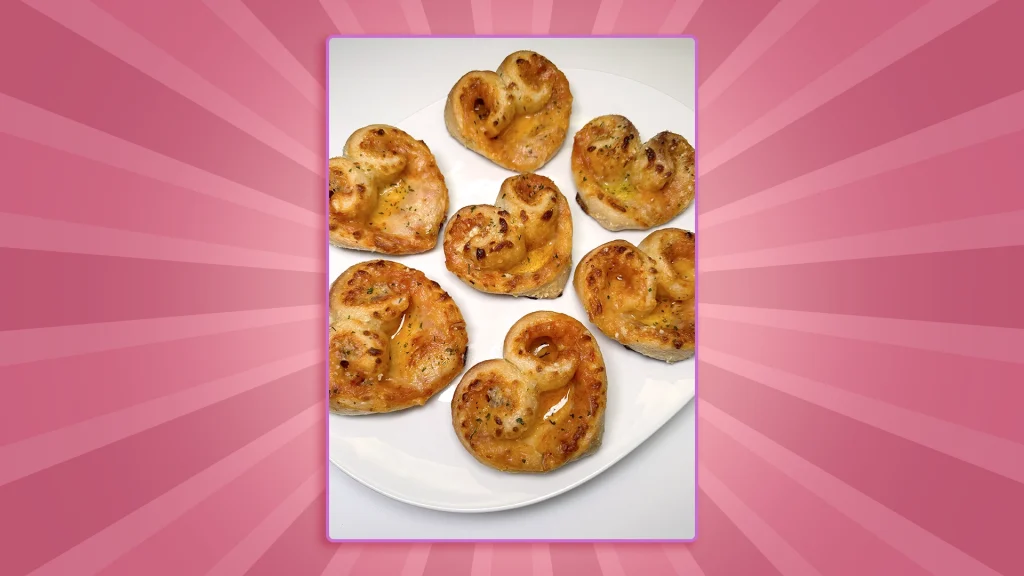 an image on a pink background shows 5 mini heart pizzas on a plate.