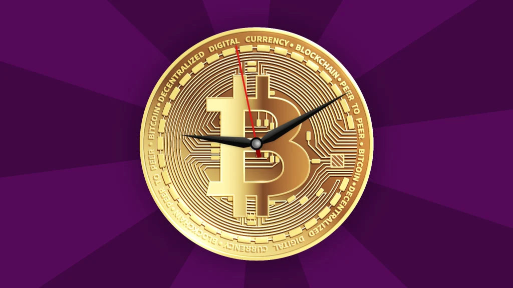 A gold Bitcoin is in the center of a dark purple image, and two clock hands are ticking in the center of the Bitcoin.