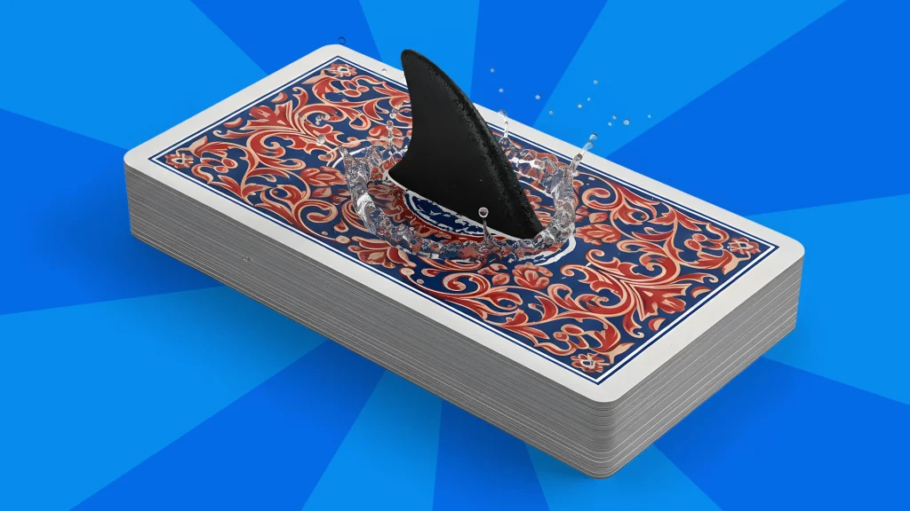 A black shark fin runs through a deck of cards in the center of a bright blue background. 