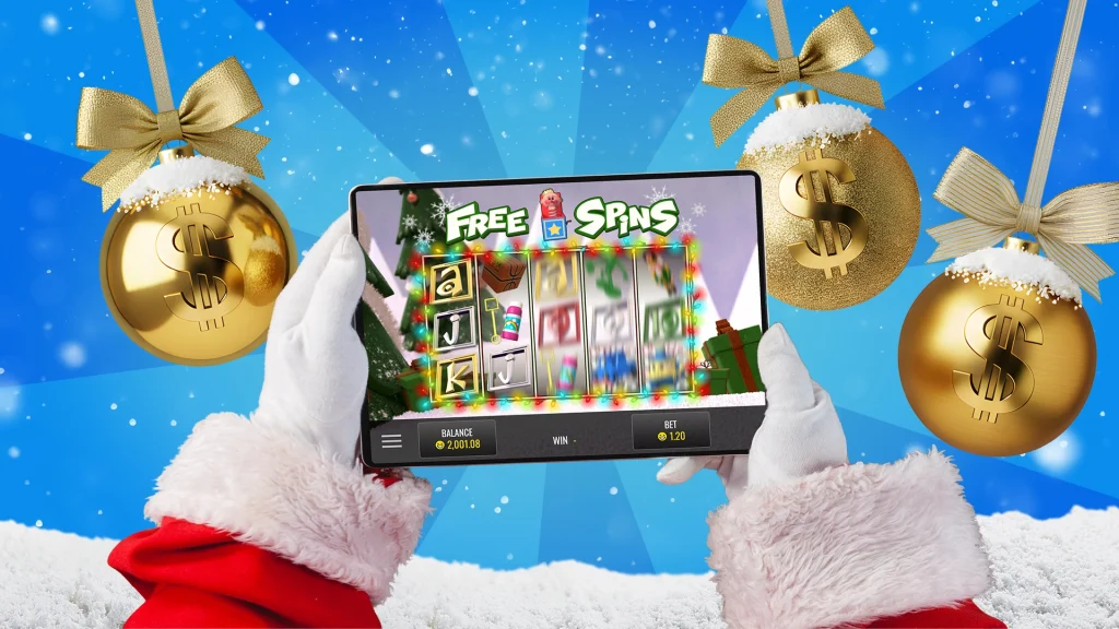 Three gold ornaments fall around Santa, who is holding a screen showing an online slot free spins game, with snow falling in the background. 