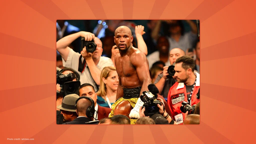 Floyd Mayweather standing shirtless in a boxing ring surrounded by photographers after a fight.