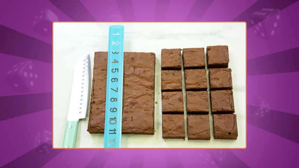A knife and a ruler on top of the brownies with half of them cut into even squares